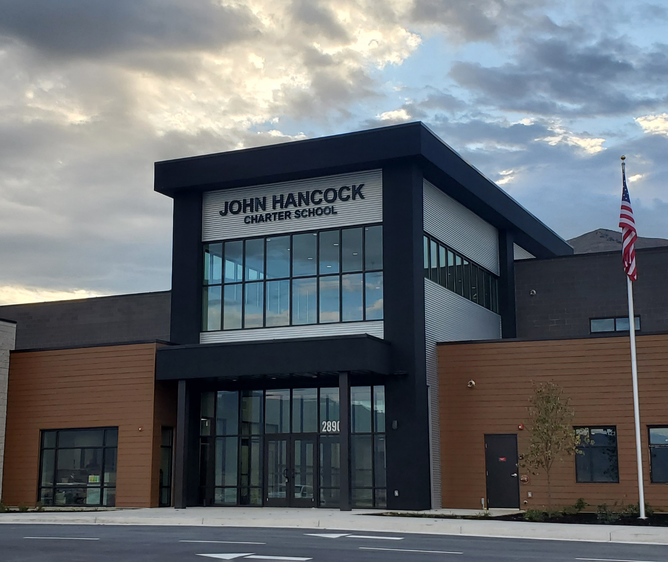 The front exterior of the John Hancock Charter School under a cloudy sky.